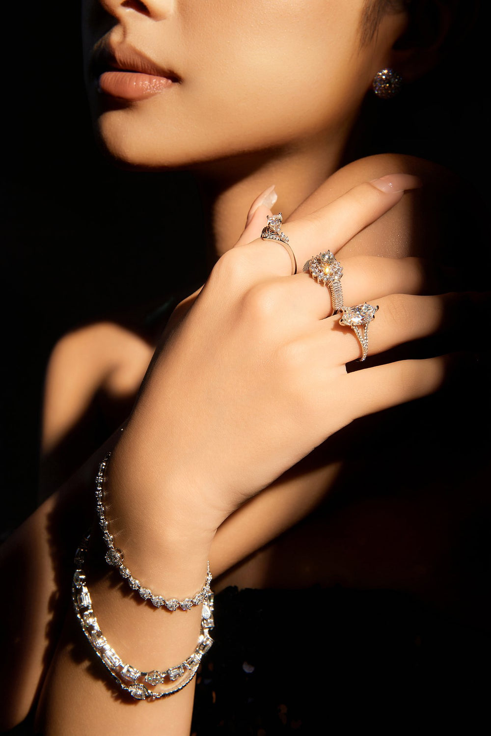 Bàn tay đeo nhẫn và vòng tay Moissanite Caterina Diamond trên nền tối