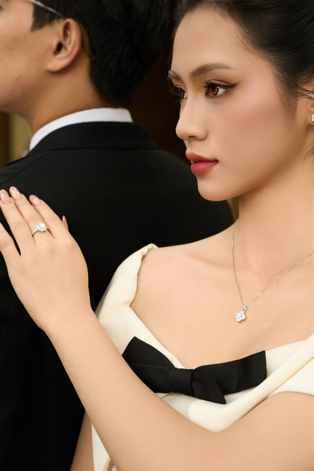 Bàn tay đeo nhẫn Moissanite Caterina Diamond đặt trên vai anh, cô ấy đeo dây chuyền